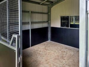 Empty animal enclosure with metal door and window.