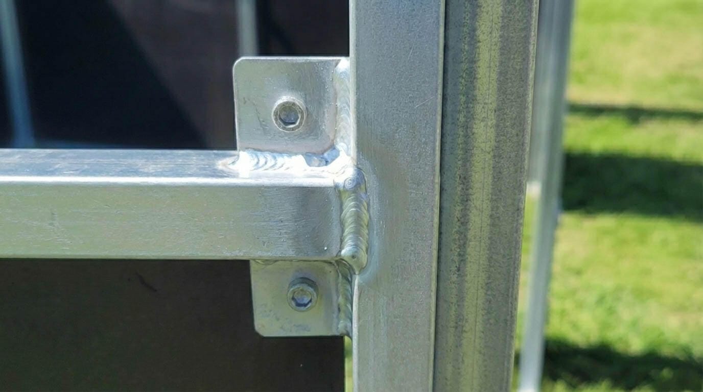 Close-up of a welded steel  stable joint connecting square hollow section steel panels with bolts.