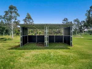 Outdoor steel animal shelter with two bays on grassy field