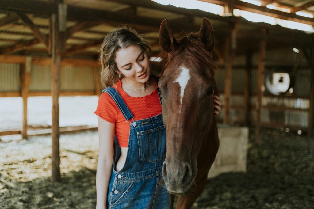 Girl and a horse inside open stable shed