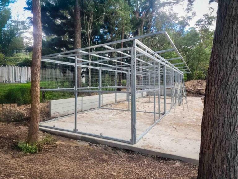 Steel frame mid-construction showing modular layout of 3-stall stable system – depicts early build stage on concrete slab.