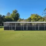 Outdoor structure on grassy field with trees behind.