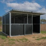 Outdoor animal shelter on grassy field under clouds.