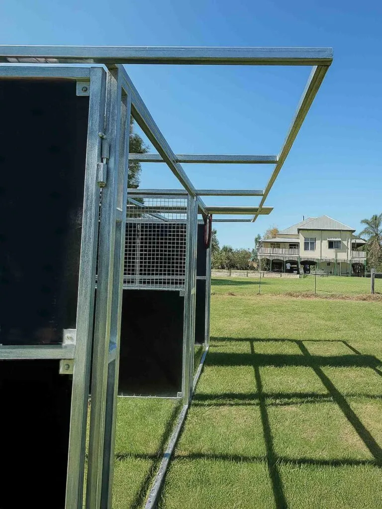 Outdoor metal cages on grassy field under blue sky.
