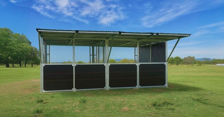 Outdoor animal shelter on grassy field under blue sky.