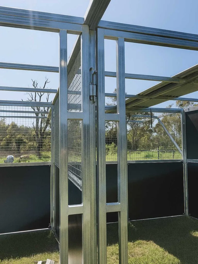 Metal farm gate with wire mesh panels.