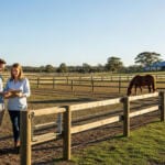 Couple discussing plans near horse paddock.