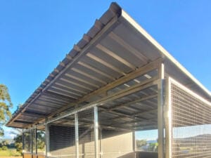 Outdoor shed with metal roof and wire mesh walls.