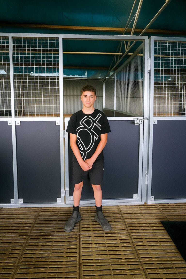 Person standing in front of horse stalls.