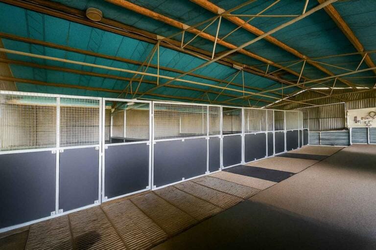 Empty equestrian stable with secure stalls inside.