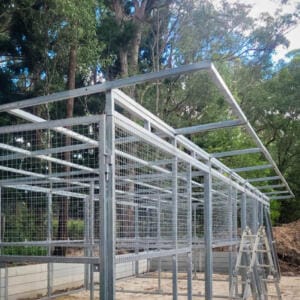 Metal aviary structure construction in forest setting.