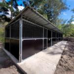 Side angle of steel stables with enclosed tack room and heavy-duty sheeting – highlights ply backing and ventilation.