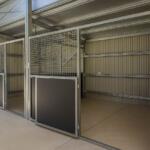 Empty metal stables with open roller door.