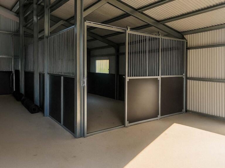 Custom indoor stable with vertical bar panels and smooth sliding gate inside shed
