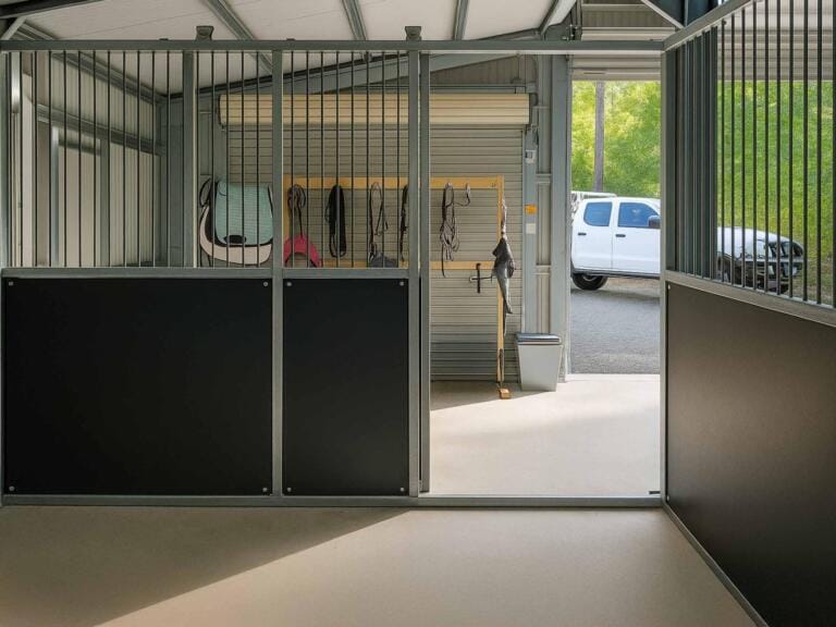 Indoor stable bay showing tack area entry and vertical bar layout from inside