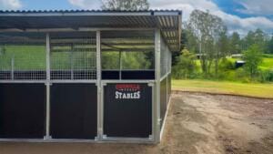 Steel stables on grassy countryside background.