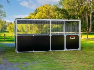 Outdoor horse stable on green field.