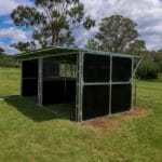 Shelter structure in a grassy field under trees.
