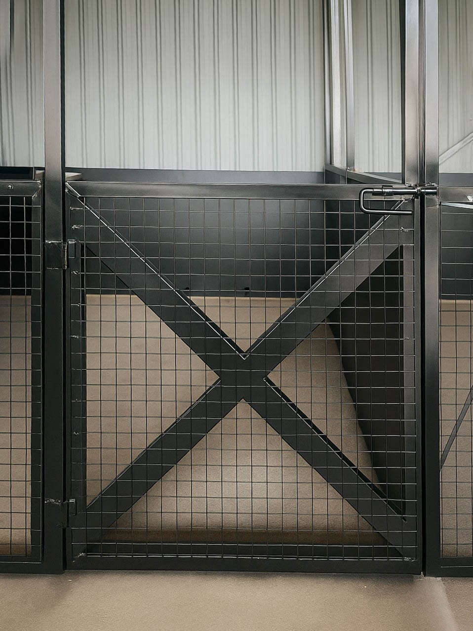 Empty black metal animal pen with lattice gate.