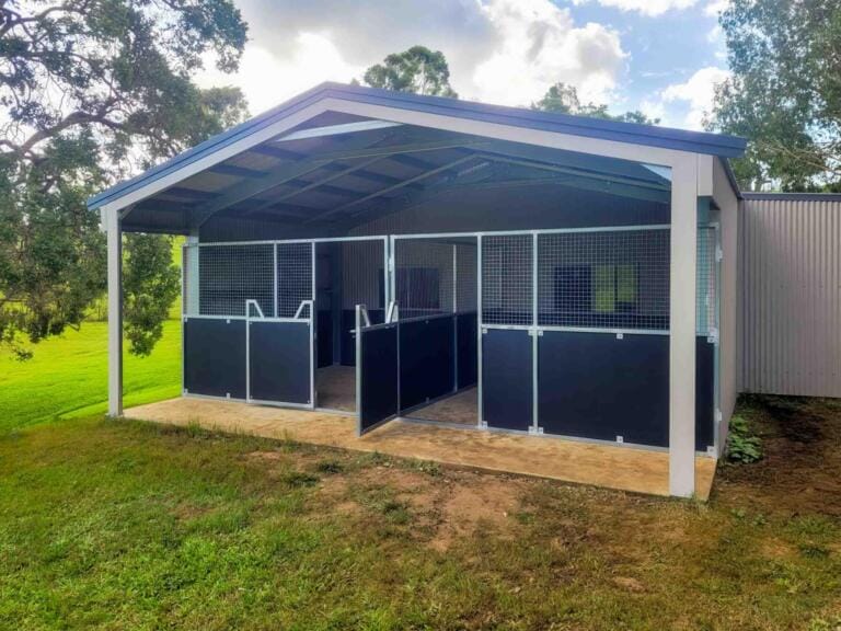 Modern outdoor horse stables in green landscape.
