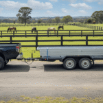 Ute with trailer carrying DIY Flatpack Stable kit near horse paddock.
