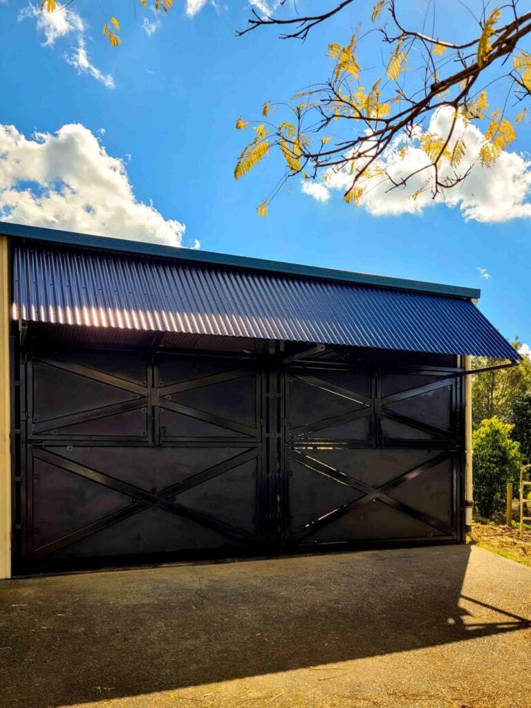 Black Custom Built Stable with breezeway, mesh gates, and reinforced panels
