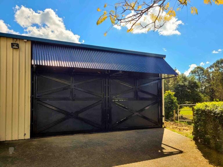 rural shed converted into black horse stable block with awning roof