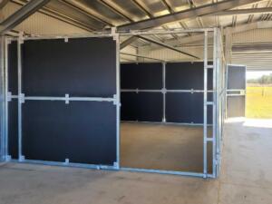 Open horse stable in metal barn building.