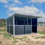Outdoor steel livestock shelter on farmland.