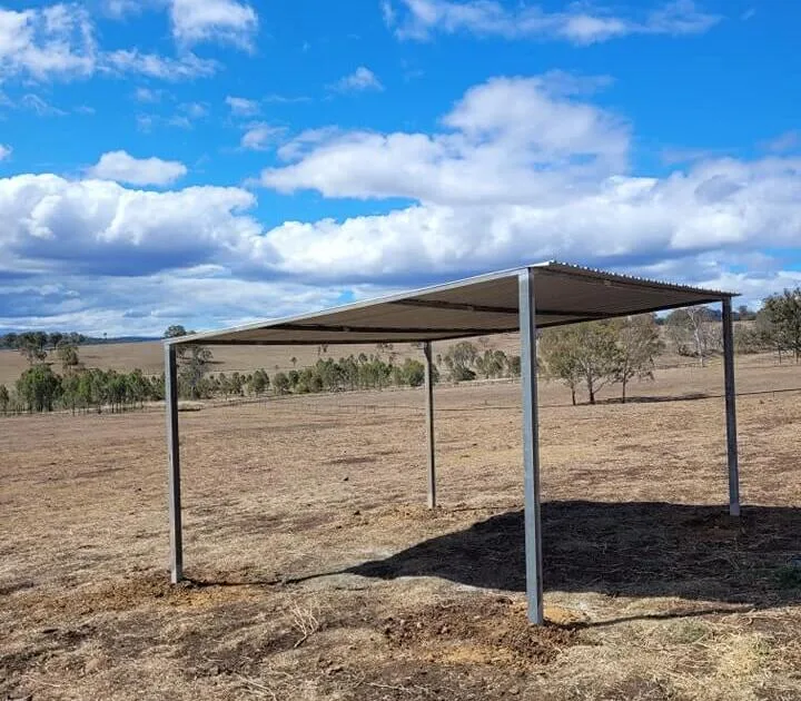 Metal shed on dry rural landscape under blue sky.