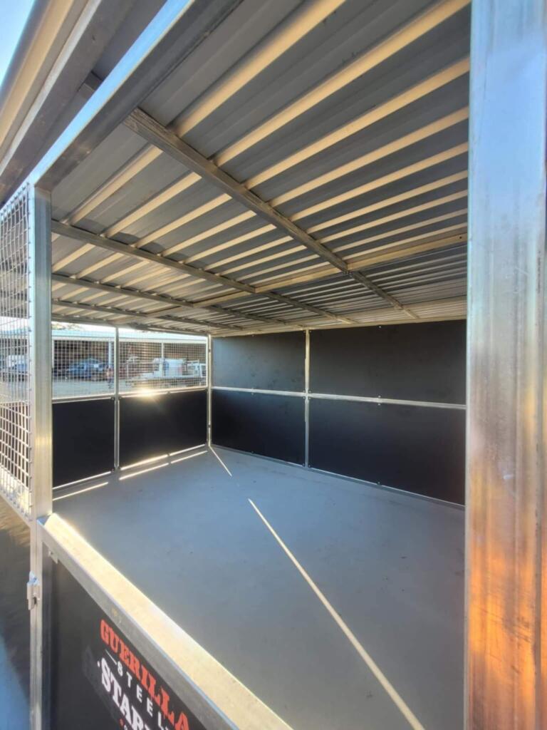 Empty steel trailer with open sides and grid panels.