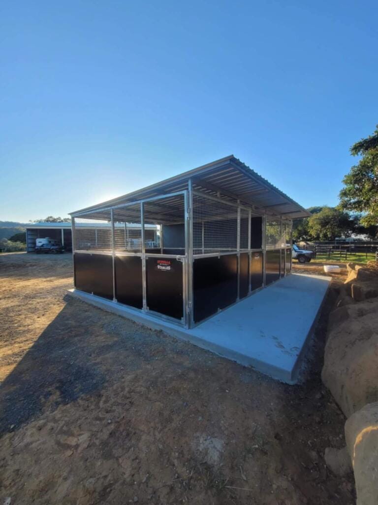 Outdoor horse stable with metal fencing.