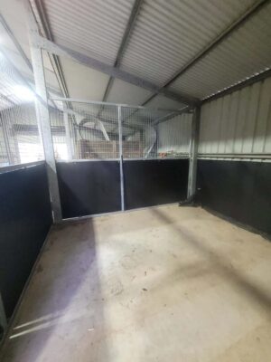 Inside single bay indoor horse stall with mesh upper panels and kickboards inside shed