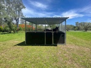 Single bay steel horse stable with roof and mesh panels in a paddock with a horse inside