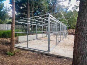 front view of modular steel horse stable with three mesh stall doors and tack room section