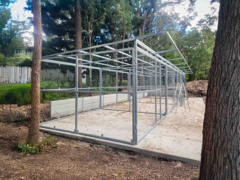 front view of modular steel horse stable with three mesh stall doors and tack room section