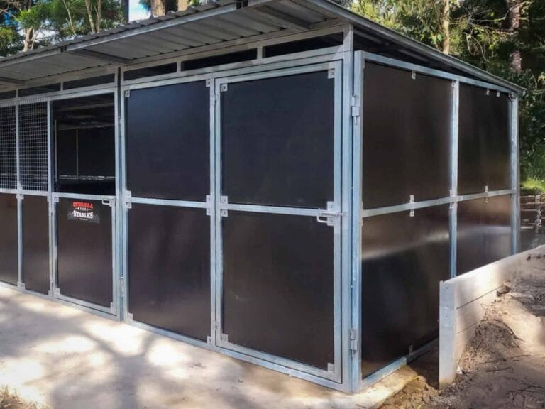 front view of modular steel horse stable with three mesh stall doors and tack room section