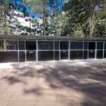 wide landscape view of 3 bay steel horse stable with tack room on open rural property