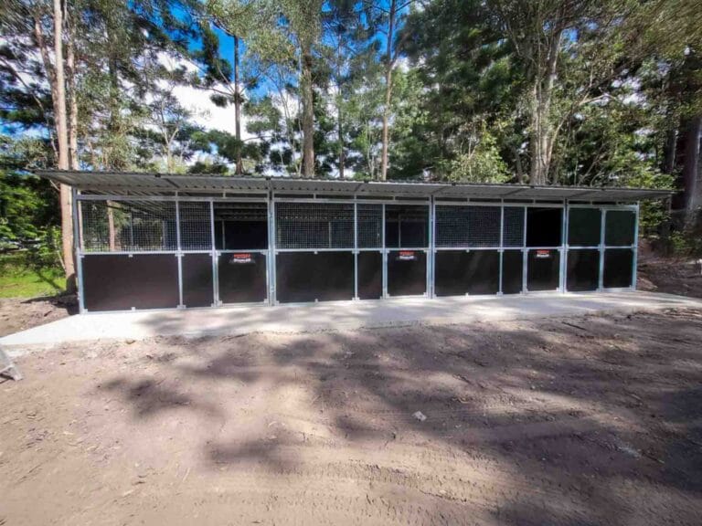 wide landscape view of 3 bay steel horse stable with tack room on open rural property