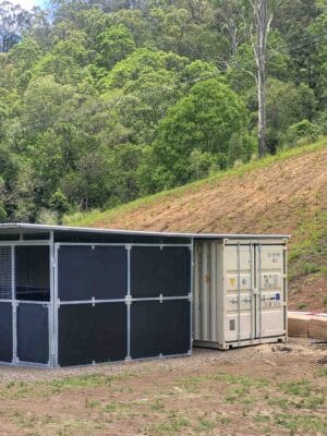 modular horse stable connected to shipping container with extended roof on rural hillside property