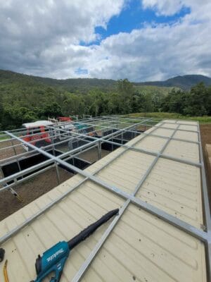 extended roof frame over modular horse stables and container creating covered walkway