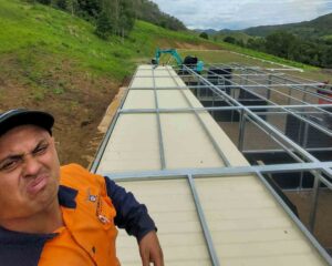 custom roof frame installation over modular horse stables and shipping container on sloping rural property